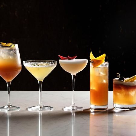 Middle Eight - Covent Garden - Preferred Hotels And Resorts London Luaran gambar The photo features a selection of five different cocktails lined up on a marble surface. Each drink is served in a distinct glass, showcasing a variety of colors and garnishes. 

1. The first cocktail is in a large wine glass, with a gradient color f
