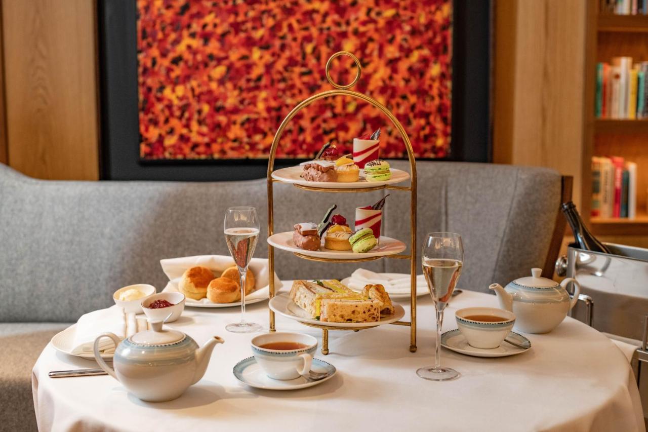 Middle Eight - Covent Garden - Preferred Hotels And Resorts London Luaran gambar The photo shows an elegant afternoon tea setup on a white tablecloth. At the center, there is a multi-tiered stand displaying a variety of pastries and desserts, including cakes and colorful sweets. Surrounding the stand are teapots and teacups, read