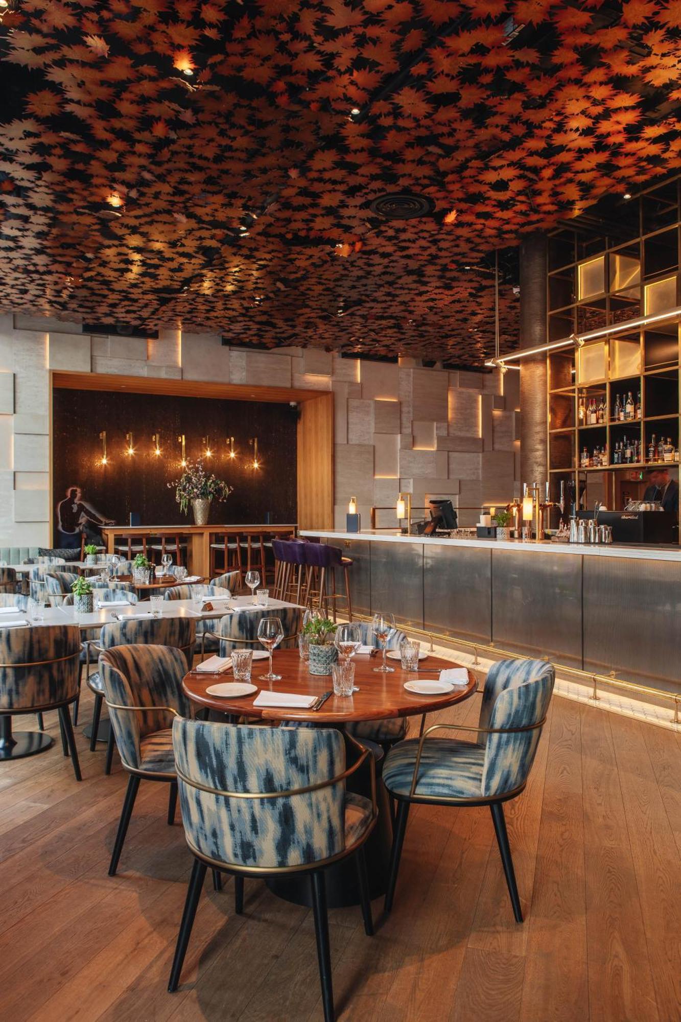 Middle Eight - Covent Garden - Preferred Hotels And Resorts London Luaran gambar The photo shows a stylish restaurant interior. There are round tables set with plates and glasses, surrounded by comfortable chairs. The bar area is sleek and modern, with a counter displaying various bottles. The lighting appears warm and inviting, 
